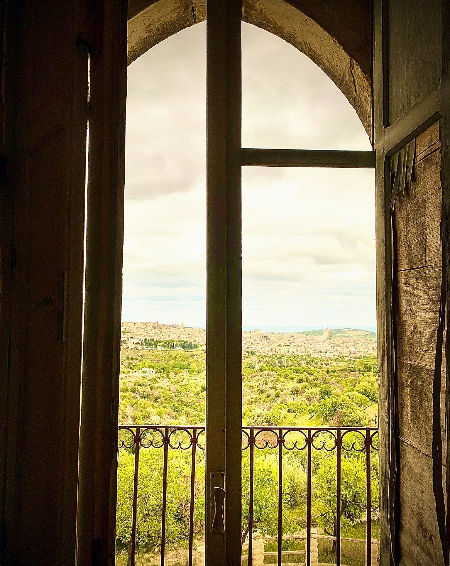 Blick durch ein Bogenfenster über die Landschaft von Noto